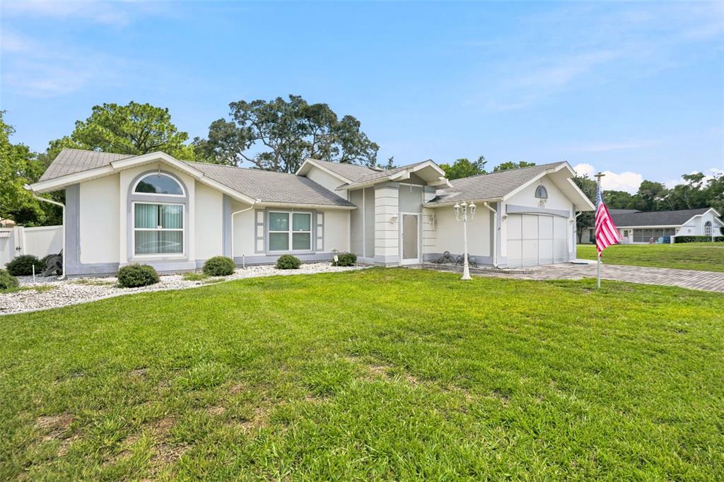 A single-story house with a white exterior, a paved driveway, and a front lawn — 11333 SILVERWOOD COURT, SPRING HILL, FL