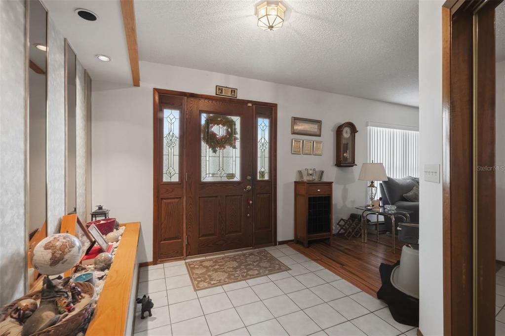 An entryway features a wood front door, tiled flooring, and a wooden console table — 11333 SILVERWOOD COURT, SPRING HILL, FL