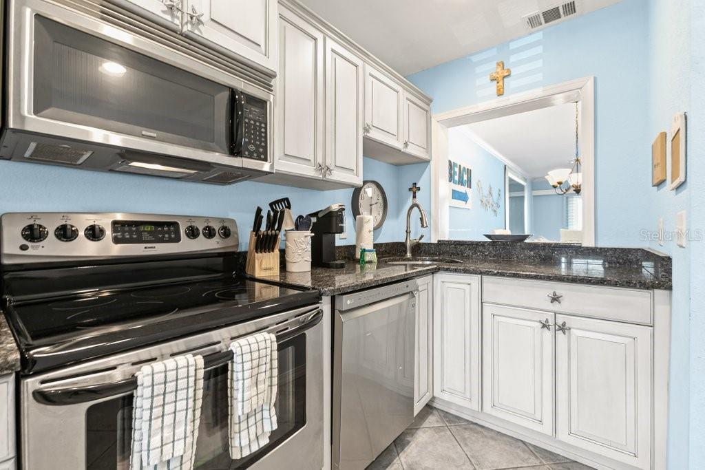 A kitchen with light blue walls, white cabinets, stainless steel appliances, and dark granite countertops — 8550 A1A #208 S UNIT 2128, ST AUGUSTINE, FL