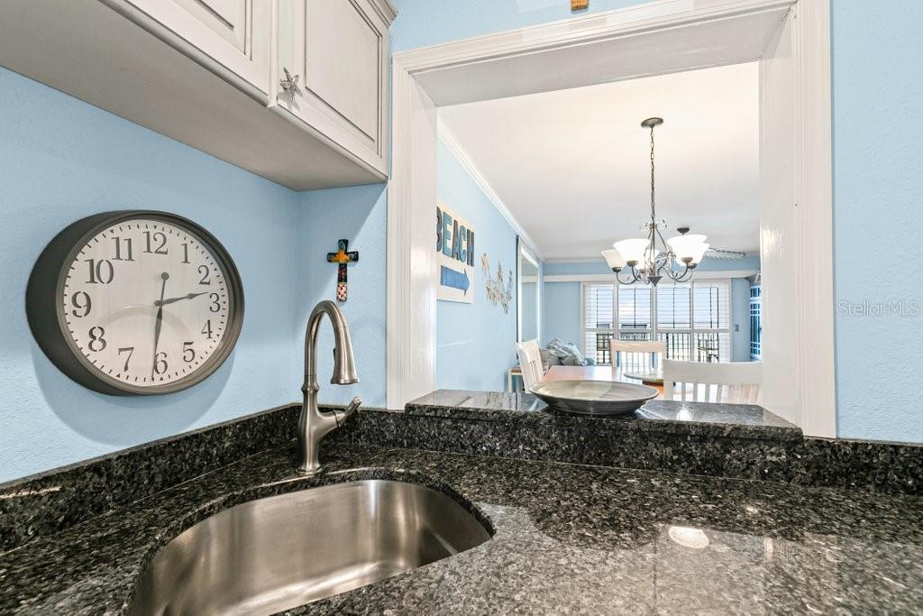 A kitchen sink with a dark granite countertop sits below a wall clock and cabinets — 8550 A1A #208 S UNIT 2128, ST AUGUSTINE, FL