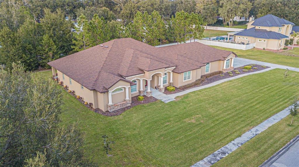 An aerial view of a tan, single-story house with a brown shingled roof and landscaping — 13102 DONE GROVEN DRIVE, DOVER, FL