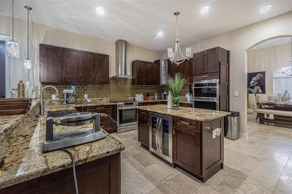 A kitchen features dark wood cabinets, granite countertops, a center island, and stainless steel appliances — 13102 DONE GROVEN DRIVE, DOVER, FL