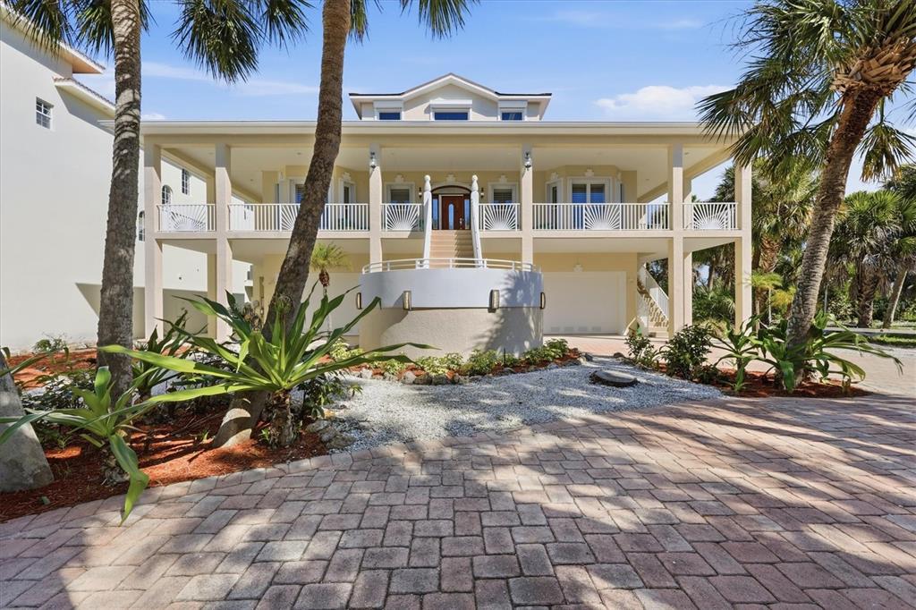 A two-story elevated house with a paved driveway, palm trees, and a central staircase — 65 PALM DRIVE, PLACIDA, FL