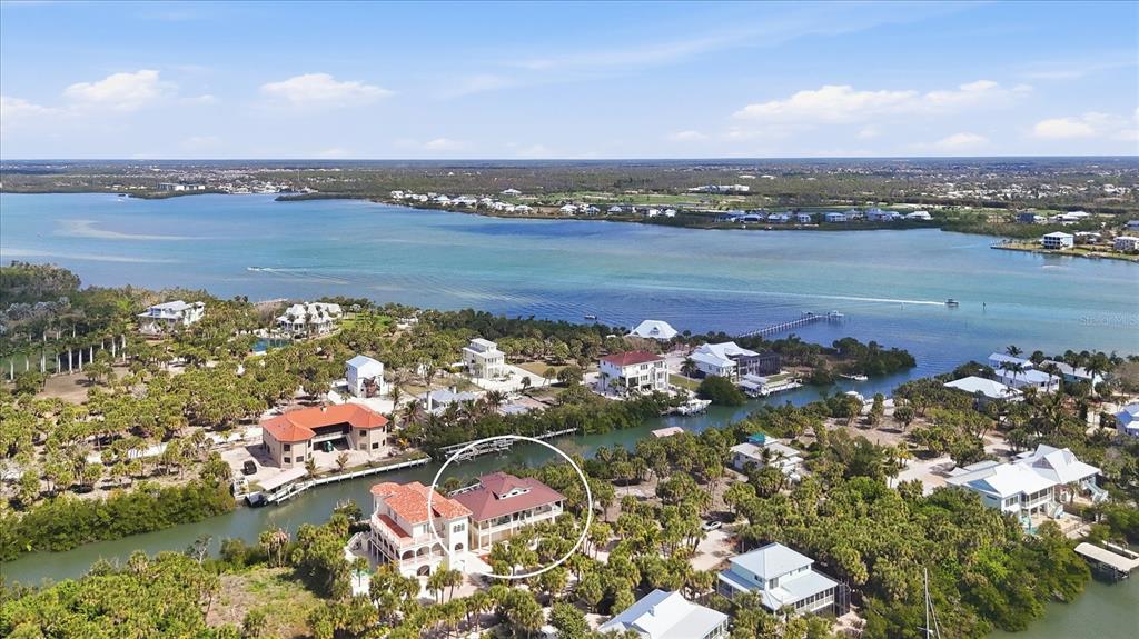 An aerial view shows a waterfront house with a red roof surrounded by lush vegetation — 65 PALM DRIVE, PLACIDA, FL