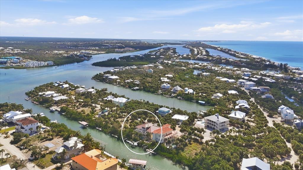 An aerial view shows a waterfront house with a pool cage along a canal — 65 PALM DRIVE, PLACIDA, FL