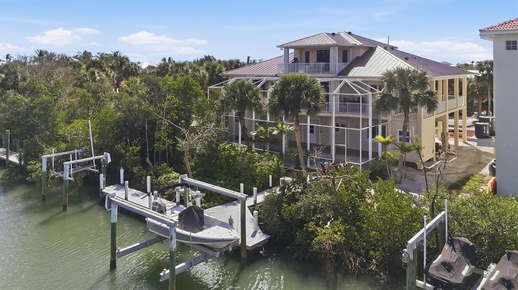 An elevated waterfront house features a screened-in porch, a boat lift, and a private dock — 65 PALM DRIVE, PLACIDA, FL