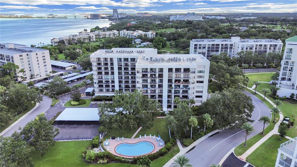 An aerial view of a multi-story apartment building with a swimming pool and parking area — 150 BELLEVIEW BOULEVARD UNIT 106, BELLEAIR, FL