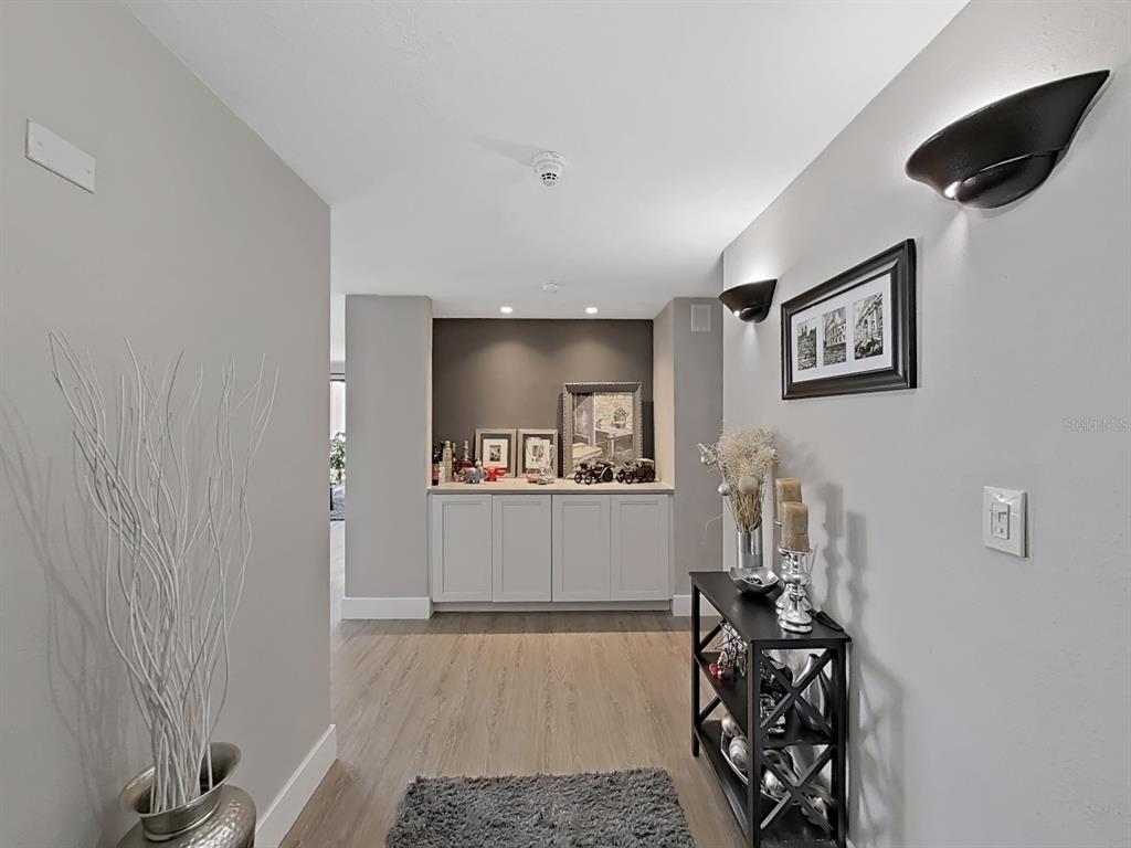 A hallway features light wood flooring, gray walls, a built-in cabinet, and wall-mounted light fixtures — 150 BELLEVIEW BOULEVARD UNIT 106, BELLEAIR, FL
