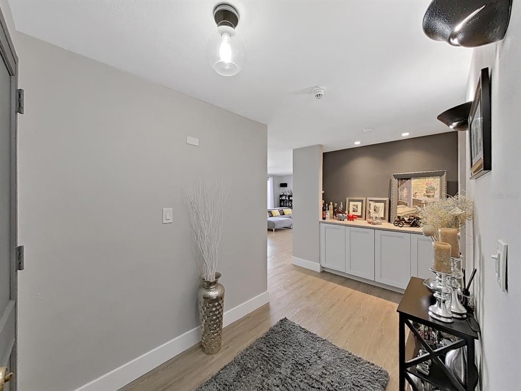 A hallway with light gray walls, wood-look flooring, a gray rug, and a built-in cabinet — 150 BELLEVIEW BOULEVARD UNIT 106, BELLEAIR, FL