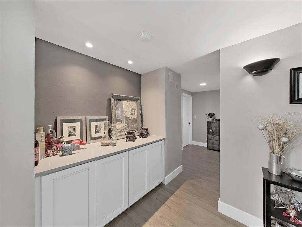 A hallway features white base cabinets with a countertop, gray walls, and wood-look flooring — 150 BELLEVIEW BOULEVARD UNIT 106, BELLEAIR, FL