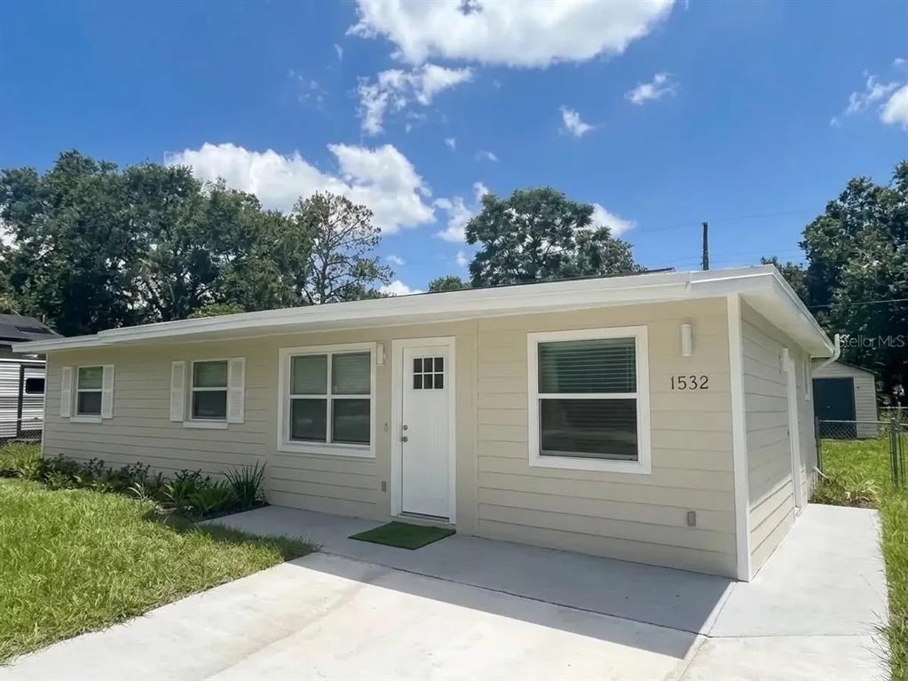 A single-story house with light tan siding, a white front door, and a concrete driveway — 1532 E VOTAW ROAD, APOPKA, FL