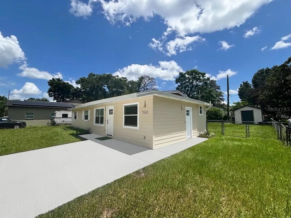 A light yellow, single-story house with a white driveway and a fenced backyard — 1532 E VOTAW ROAD, APOPKA, FL