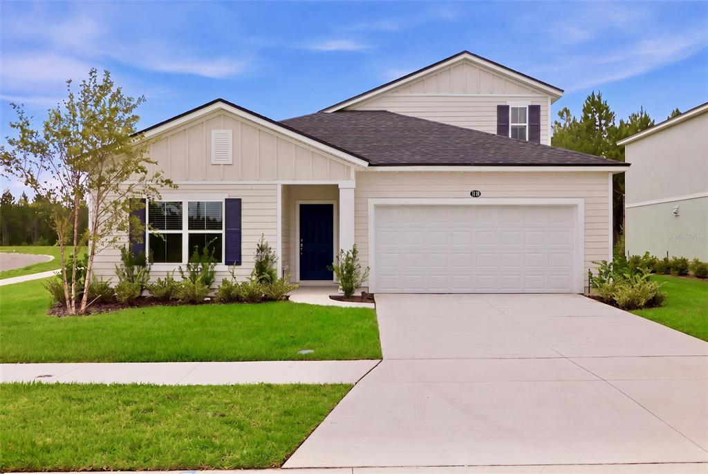 A single-story house with beige siding, a blue front door, and a two-car garage — 3778 HOLSTEIN WAY, GREEN COVE SPRINGS, FL