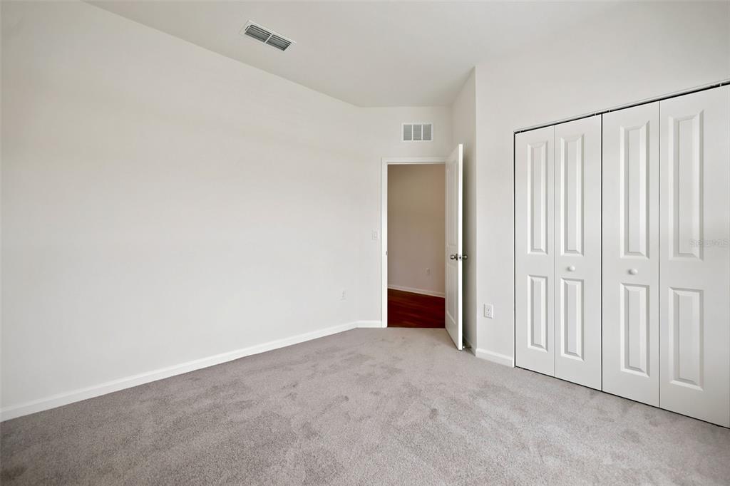 An empty bedroom with gray carpet, white walls, a closet with bifold doors, and an open doorway — 3778 HOLSTEIN WAY, GREEN COVE SPRINGS, FL