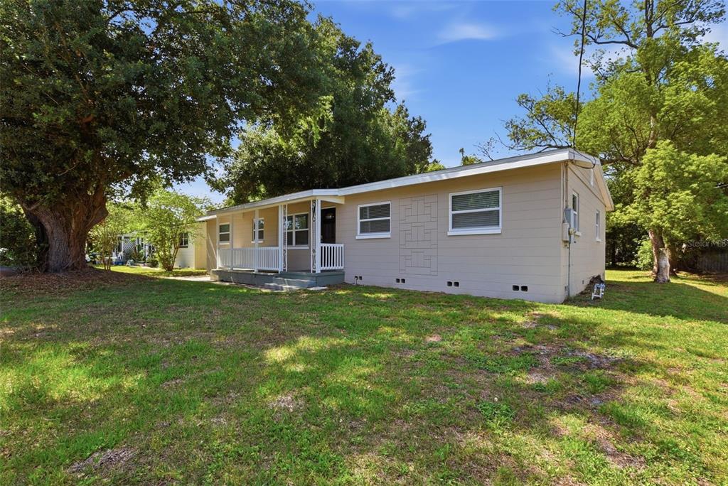 A single-story tan house with a front porch sits on a grassy lot with trees — 3521 ARCH STREET, ORLANDO, FL