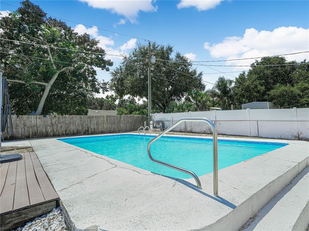 An outdoor rectangular swimming pool with a metal handrail and concrete deck — 437 BROWARD TERRACE, WINTER HAVEN, FL