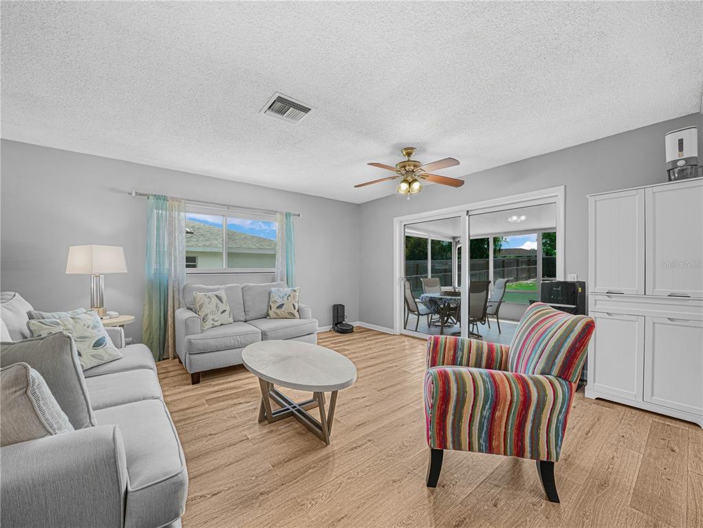 A living room features light wood flooring, a ceiling fan, and sliding glass doors to a patio — 437 BROWARD TERRACE, WINTER HAVEN, FL
