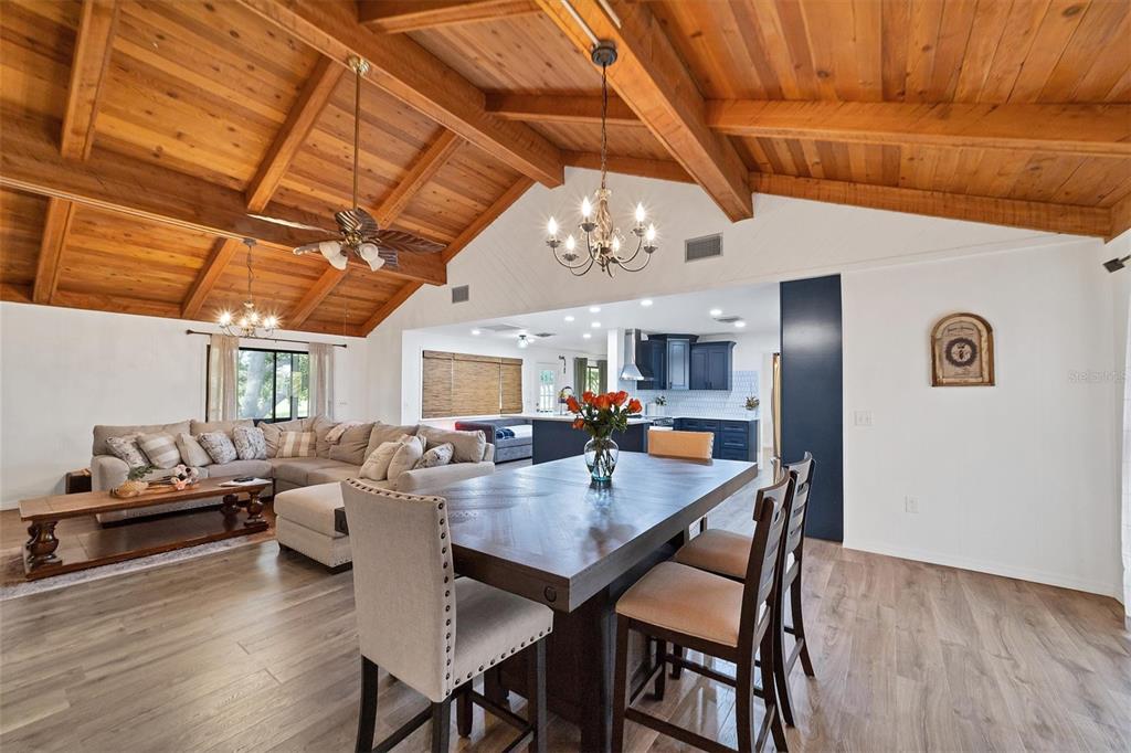 A dining area and living room with a vaulted wood-beamed ceiling and open kitchen — 18 PEBBLE BEACH ROAD, ROTONDA WEST, FL
