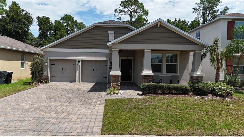 A single-story house with a two-car garage, stone-accented columns, and a paved driveway — 383 BRUNSWICK DRIVE, DAVENPORT, FL