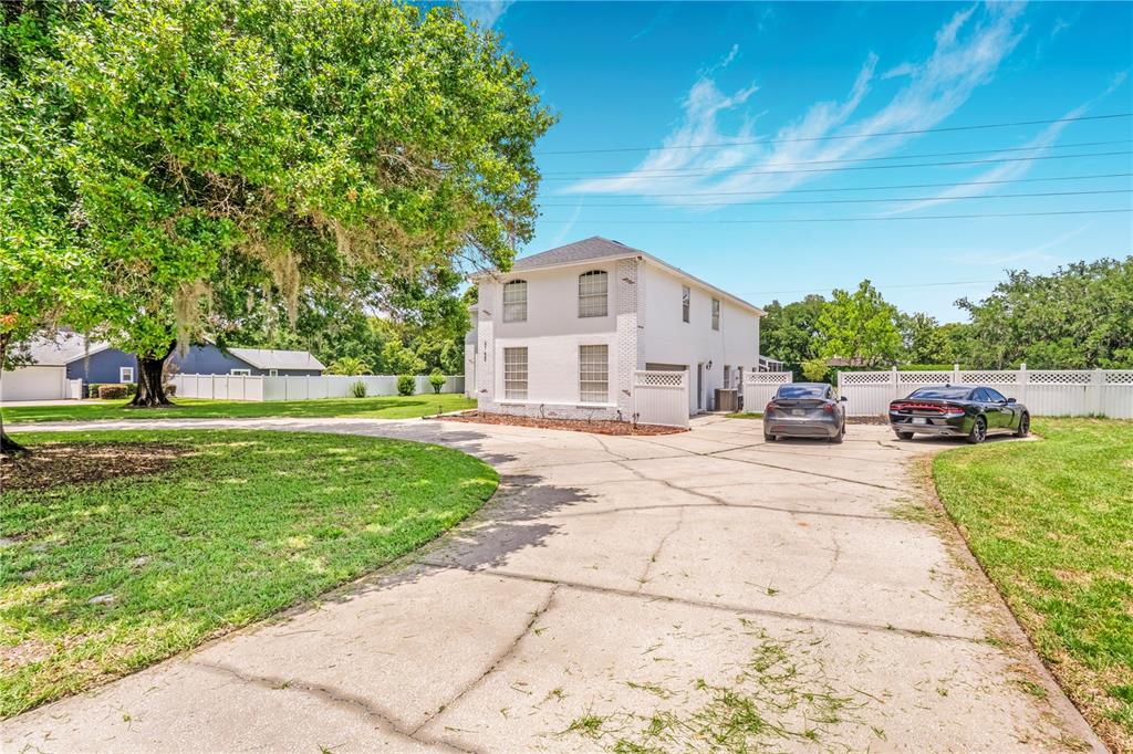 A two-story white house with a large concrete driveway and two parked cars — 2152 BLUE IRIS PLACE, LONGWOOD, FL