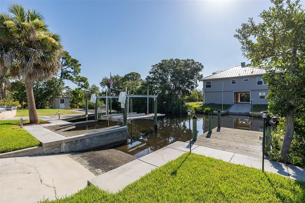 A backyard features a boat lift, a wooden dock, and a house on a canal — 3318 PINEVIEW DRIVE, HOLIDAY, FL