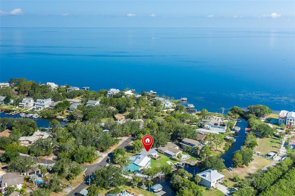 An aerial view shows a waterfront house with a pool near a canal and bay — 3318 PINEVIEW DRIVE, HOLIDAY, FL