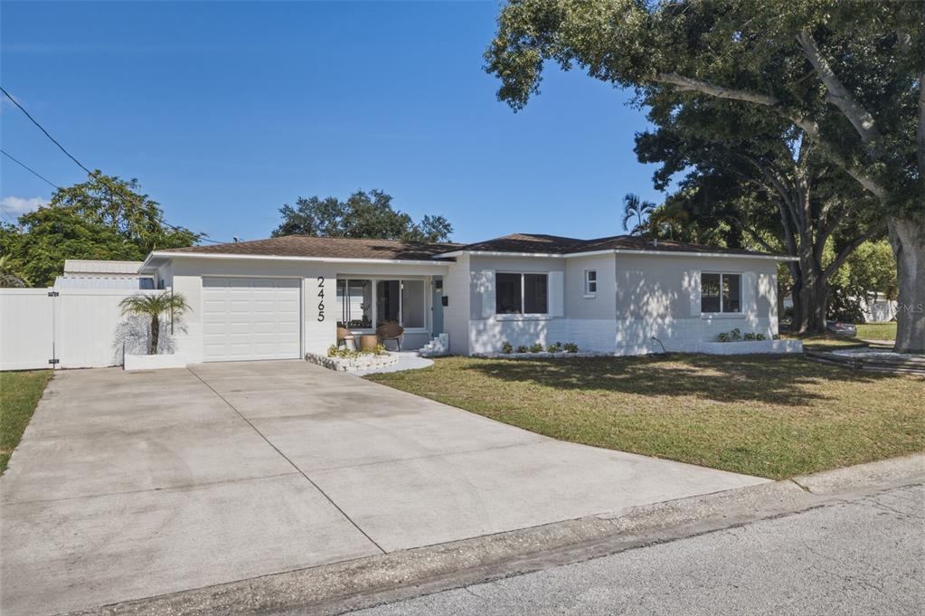 A single-story house with a white exterior, a concrete driveway, and a large shade tree — 2465 38TH STREET N, ST PETERSBURG, FL