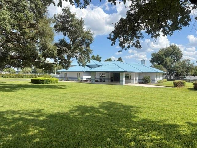 A single-story house with a blue metal roof sits on a large, grassy lawn — 2241 WINTERSET ROAD, WINTER HAVEN, FL