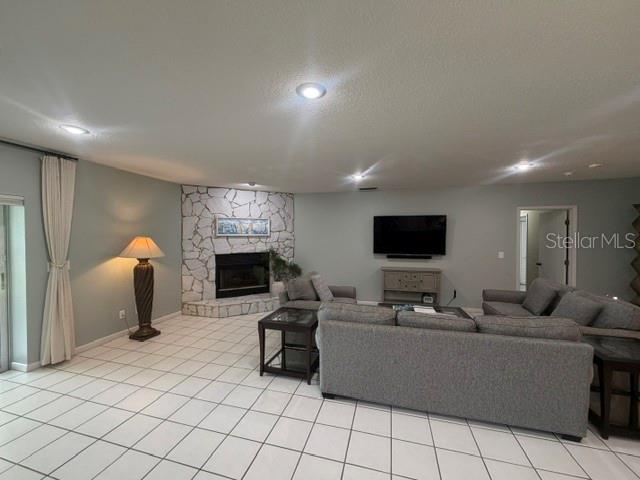 A living room features a stone fireplace, gray sofa, and white tile flooring — 2241 WINTERSET ROAD, WINTER HAVEN, FL