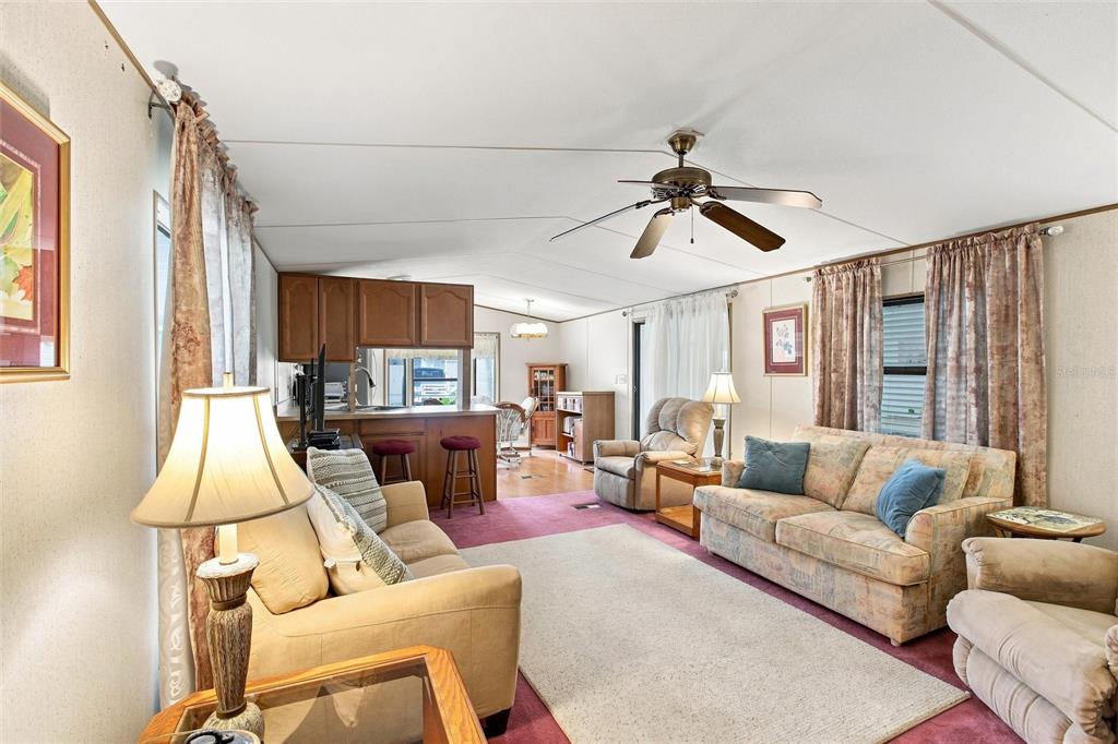 A living room features a beige sofa, a patterned couch, a ceiling fan, and carpeting — 238 EGRET, PUNTA GORDA, FL
