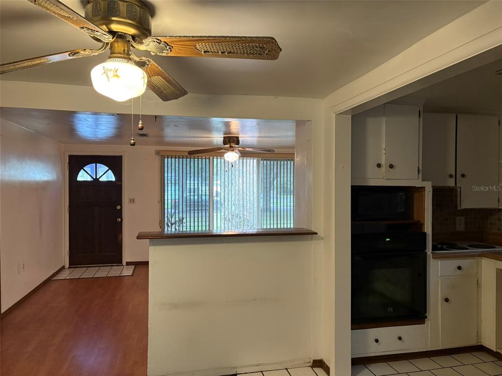 A kitchen with white cabinets, a built-in oven, and a breakfast bar overlooking a living area — 671 DEXTER DRIVE, DUNEDIN, FL