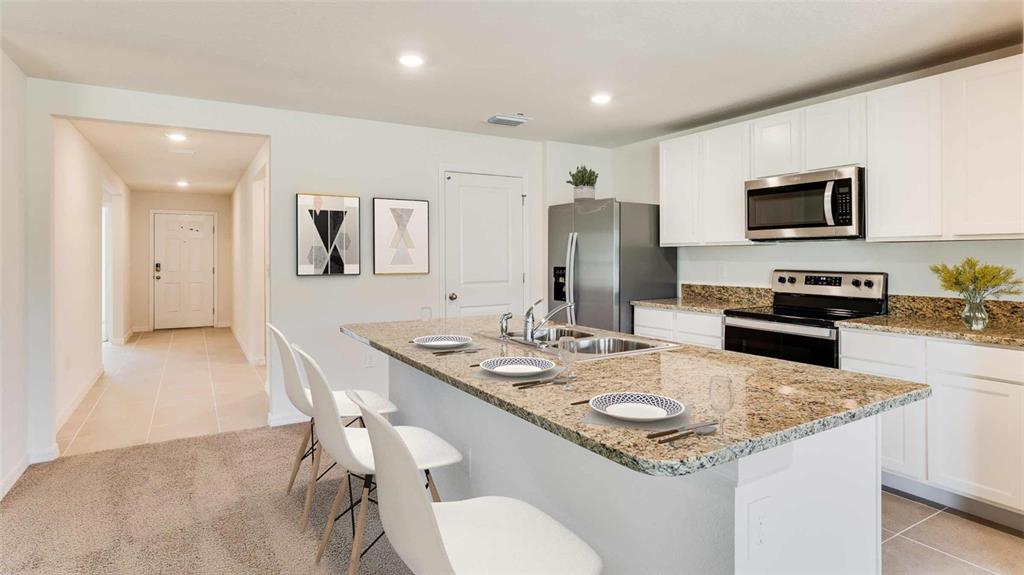 A kitchen features white cabinets, granite countertops, a center island with seating, and stainless appliances — 3524 HARVEST GARDENS LOOP, PLANT CITY, FL