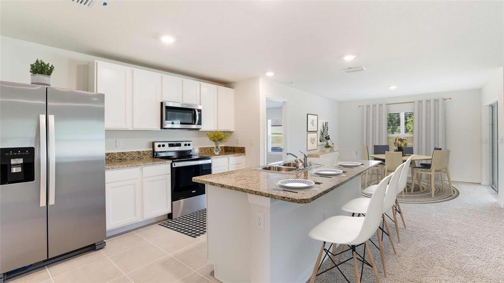 A kitchen with white cabinets, granite countertops, stainless steel appliances, and an island with seating — 3524 HARVEST GARDENS LOOP, PLANT CITY, FL