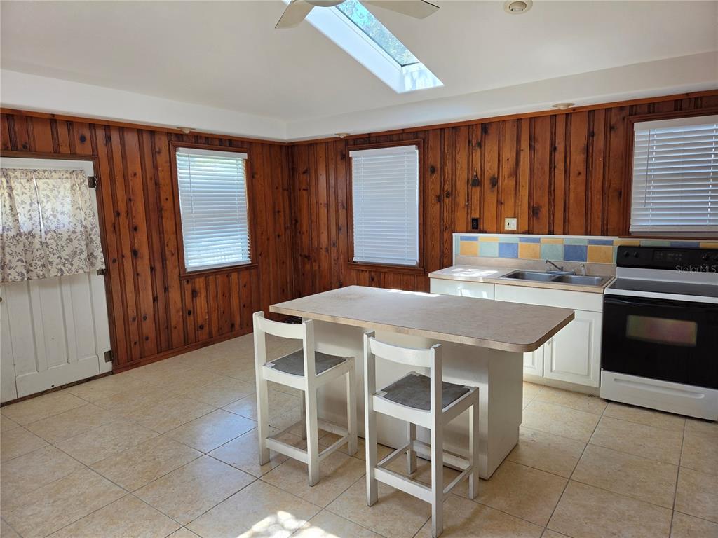 A kitchen features wood-paneled walls, a central island with two chairs, and a skylight — 5023 27TH AVENUE S, GULFPORT, FL