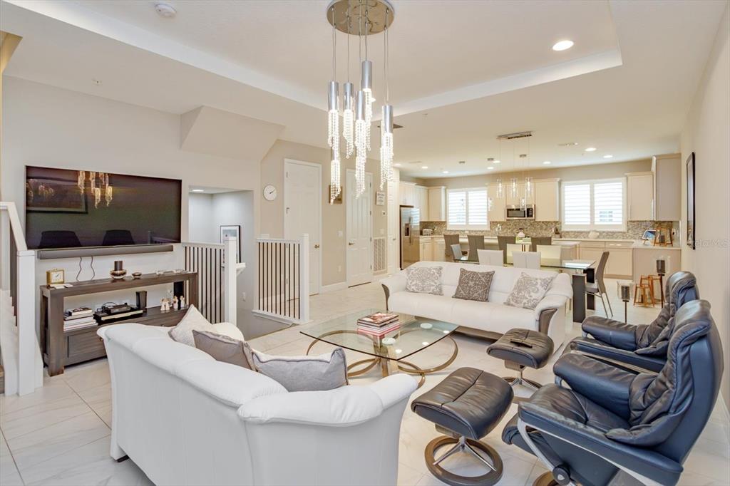 An open-concept living room features white sofas, leather recliners, and a modern crystal chandelier — 1495 LAKE GEORGE DRIVE, LAKE MARY, FL