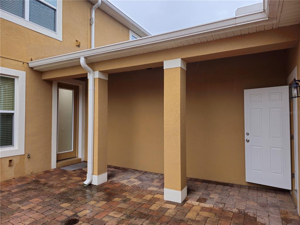 A covered patio with paver flooring, two support columns, and two white exterior doors — 8470 IRON MOUNTAIN TRAIL, WINDERMERE, FL