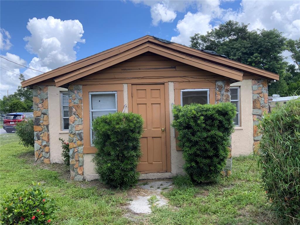 The exterior of a small, single-story house features stone accents, a brown door, and two bushes — 2118 1ST AVENUE E, PALMETTO, FL