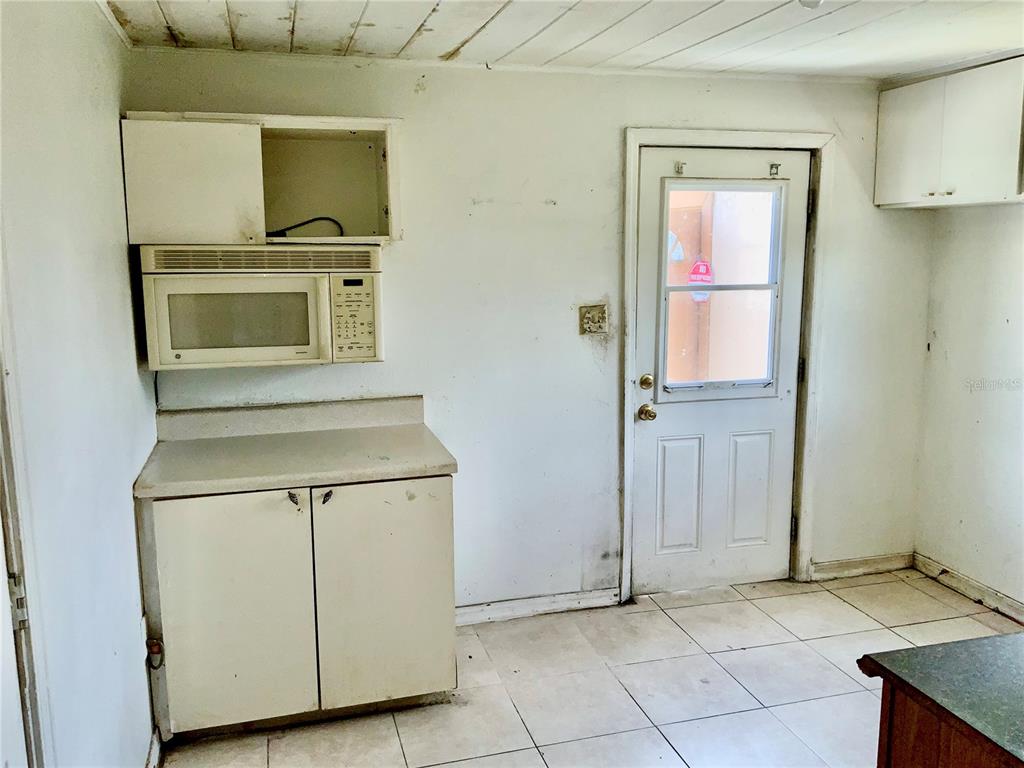 A kitchen with white cabinets, a built-in microwave, tile flooring, and a glass-paneled exterior door — 2118 1ST AVENUE E, PALMETTO, FL