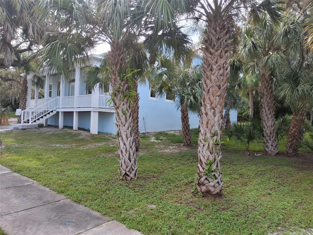 A raised house with a front porch, wooden stairs, and a concrete walkway — 383 GEORGIA AVENUE, CRYSTAL BEACH, FL