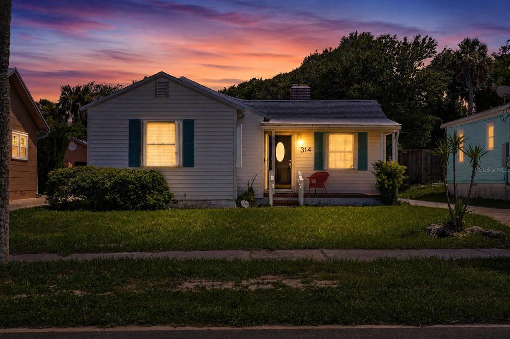 A single-story house with light siding, blue shutters, and a front porch at dusk — 314 REVILO BOULEVARD, DAYTONA BEACH, FL