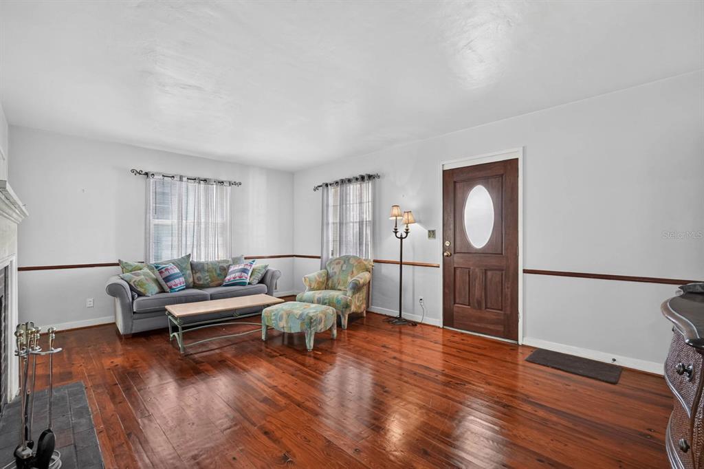 A living room features hardwood floors, a gray sofa, an armchair, and a wooden door — 314 REVILO BOULEVARD, DAYTONA BEACH, FL