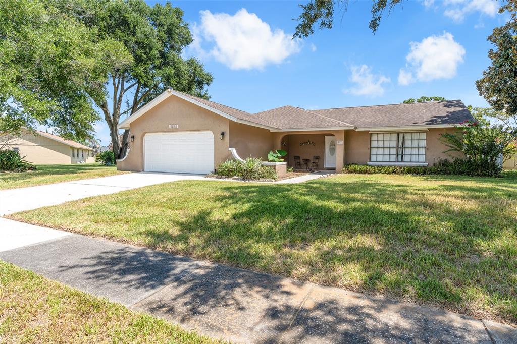 A single-story tan house with a two-car garage, a covered entryway, and a front lawn — 8971 ANGELICA DRIVE, ORLANDO, FL
