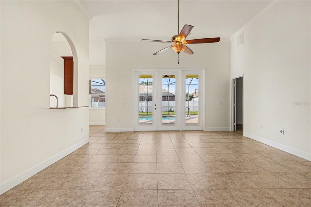 A spacious living room features tile flooring, a ceiling fan, and glass doors to a pool — 314 TERRANOVA BOULEVARD, WINTER HAVEN, FL