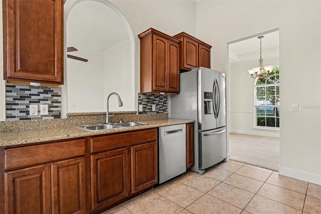 A kitchen features wood cabinets, granite countertops, stainless steel appliances, and a tiled backsplash — 314 TERRANOVA BOULEVARD, WINTER HAVEN, FL