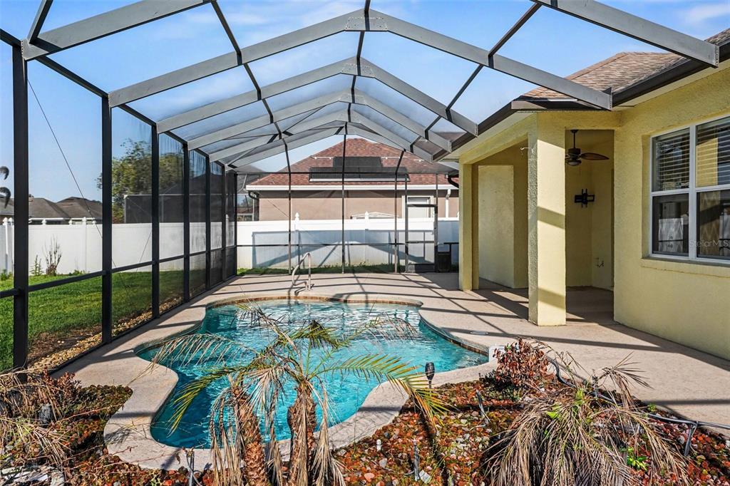 A screened-in swimming pool and patio area attached to the back of a yellow house — 314 TERRANOVA BOULEVARD, WINTER HAVEN, FL