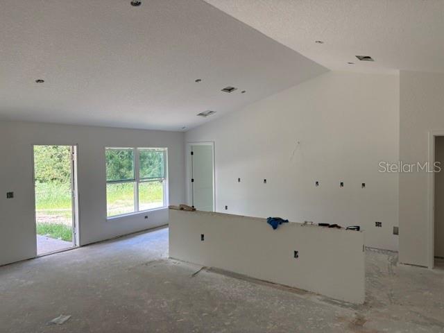 An unfinished room with a vaulted ceiling, a half wall, and a sliding glass door — 6734 SW 179TH AVENUE ROAD, DUNNELLON, FL