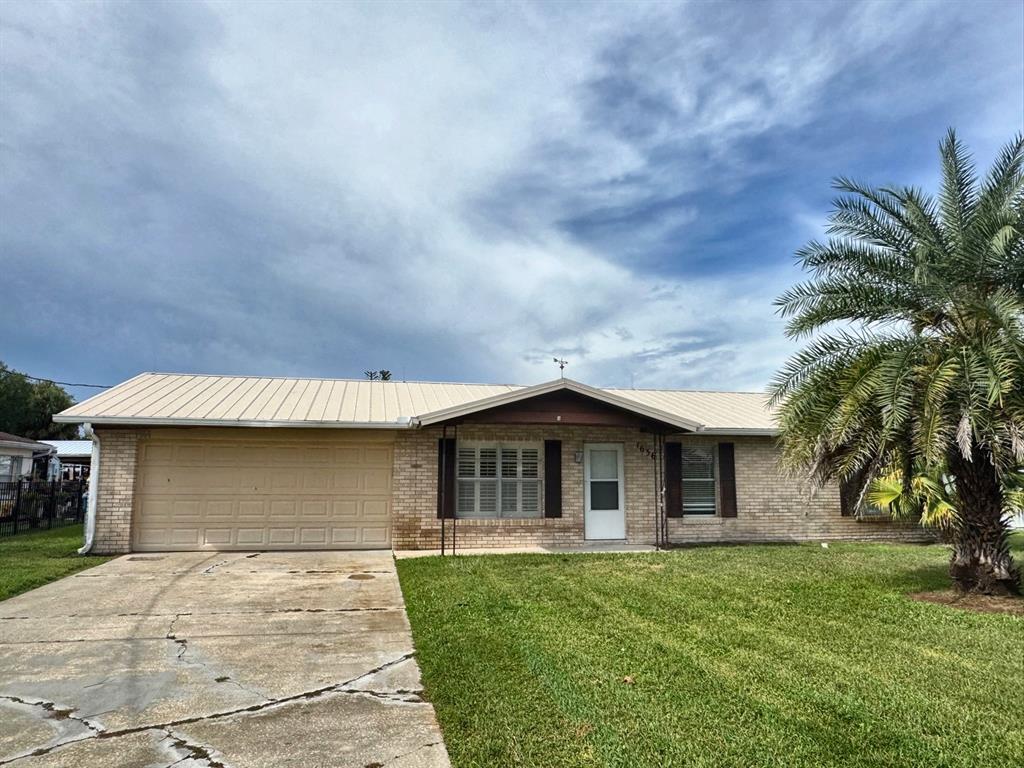 A single-story brick house with a metal roof, attached garage, and a palm tree — 1636 JUNO TRAIL, ASTOR, FL