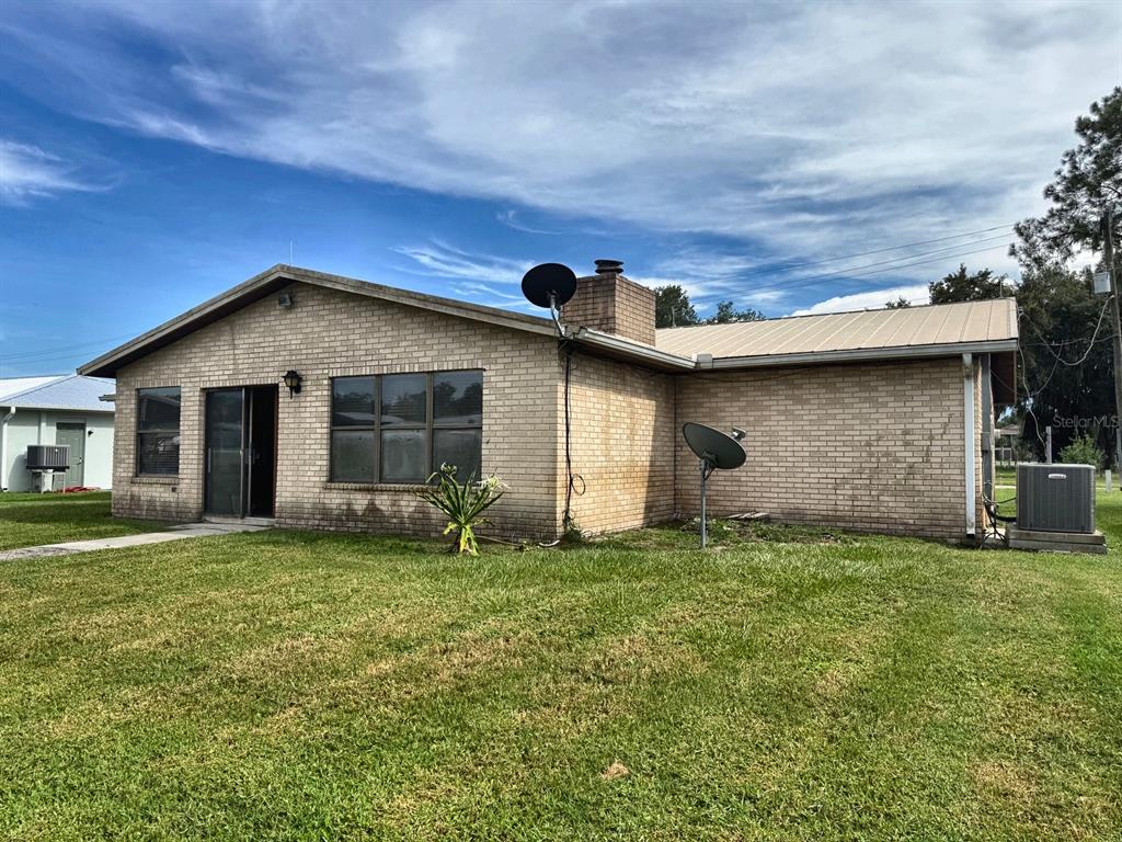 A single-story brick house with a metal roof and two satellite dishes on the lawn — 1636 JUNO TRAIL, ASTOR, FL