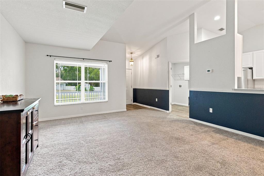 A living room with gray carpet, white walls, blue wainscoting, and a large window — 10041 KIMBROUGH DRIVE, BROOKSVILLE, FL