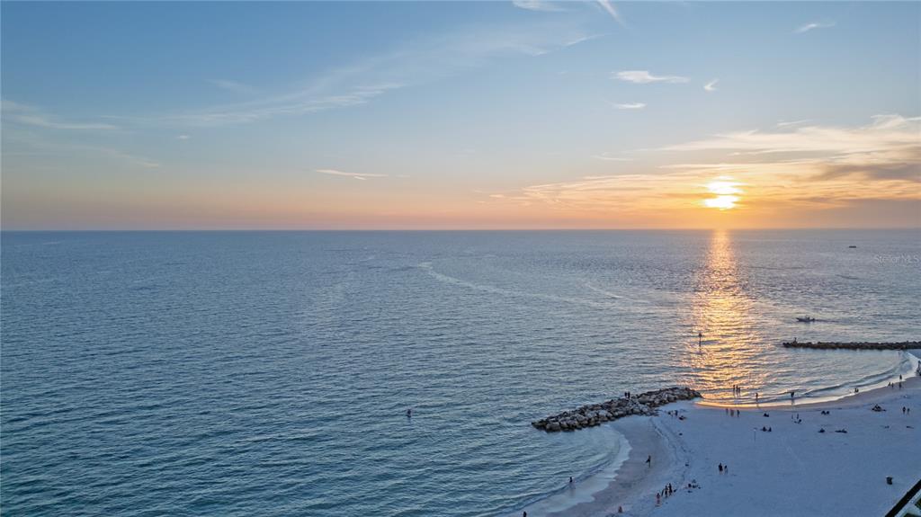 An aerial view shows a beachfront condominium building with a green arrow pointing to a unit — 7000 BEACH PLAZA UNIT 202, ST PETE BEACH, FL
